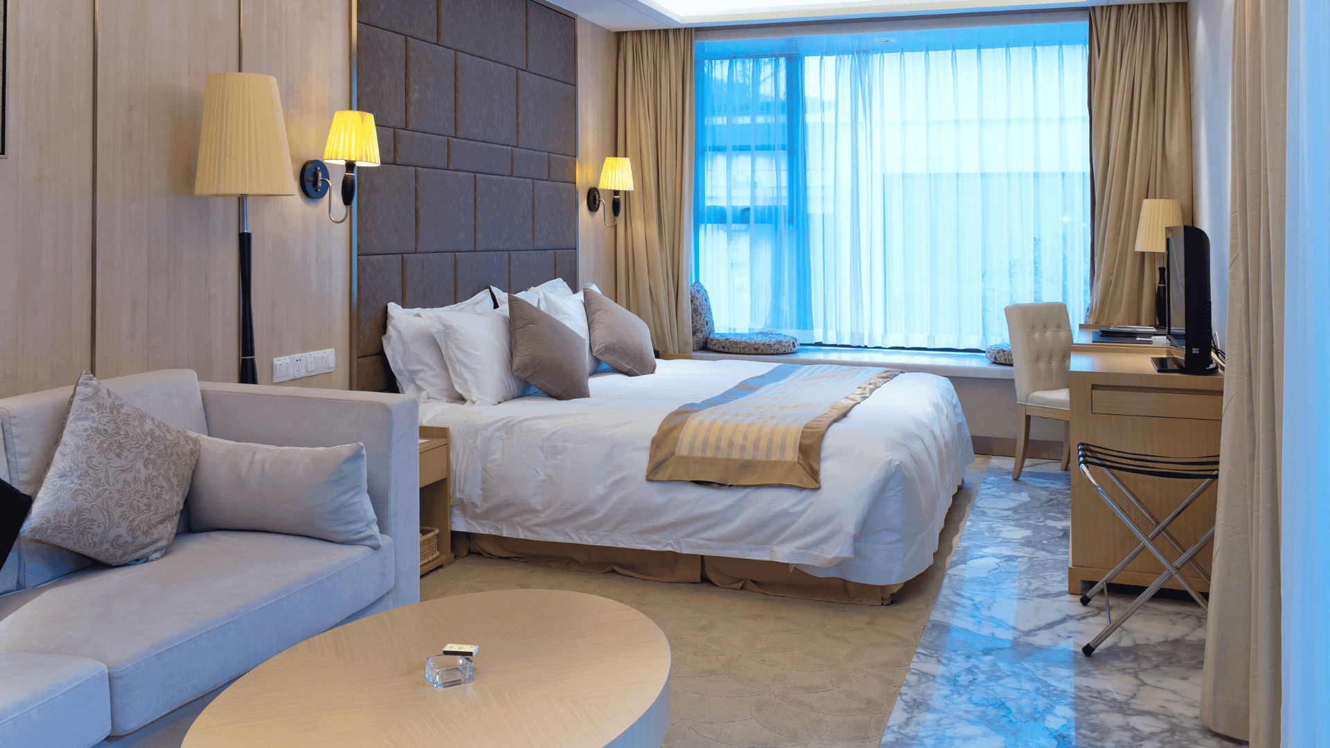 Luxury furnished bedroom for short stay in Gurgaon with modern interiors, work desk, and natural light.