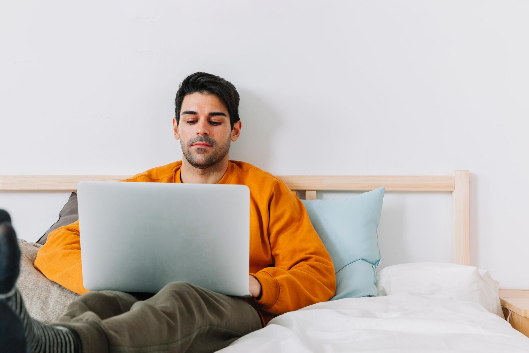Young man working on a laptop from a cozy bedroom during a short stay in Gurgaon.